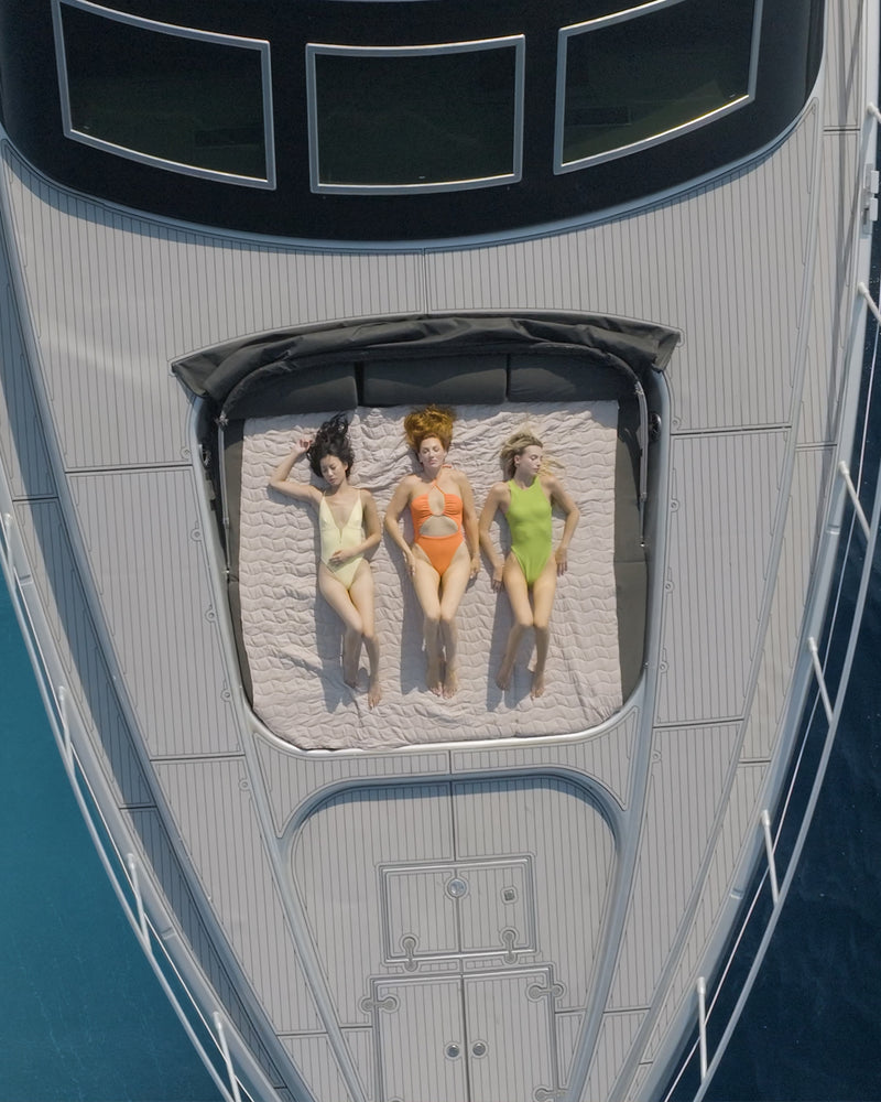 Drei Frauen in farbenfrohen Badeanzügen entspannen auf einer Yacht – mediterranes Sommergefühl im LOLA Lifestyle.