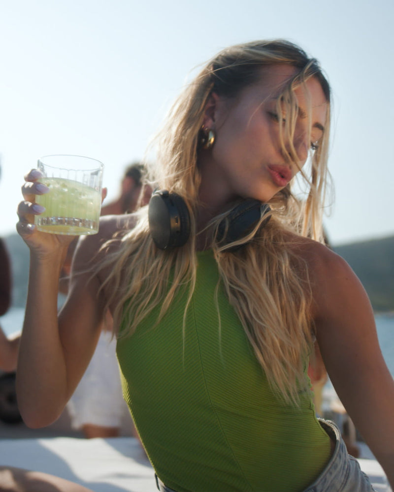 LOLA LEMON Aperitif-Flasche neben einem eisgekühlten Zitronendrink mit frischer Zitronenscheibe.